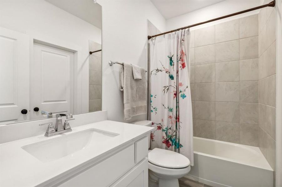 Guest Bathroom featuring shower / bath combo with shower curtain, toilet, and vanity