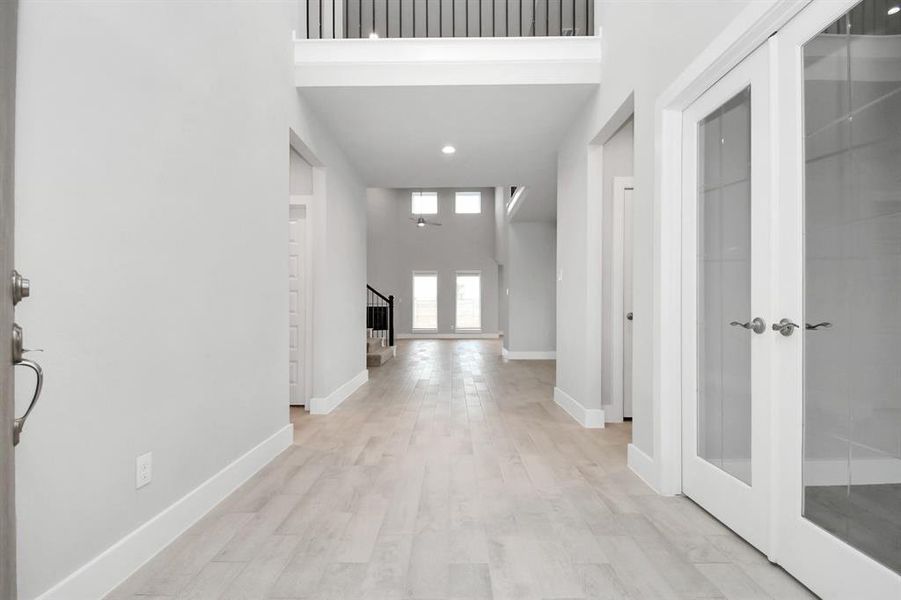 The majestic entryway allures with its high ceilings, embellished with sophisticated wood-look tile flooring and sleek oversized baseboards.