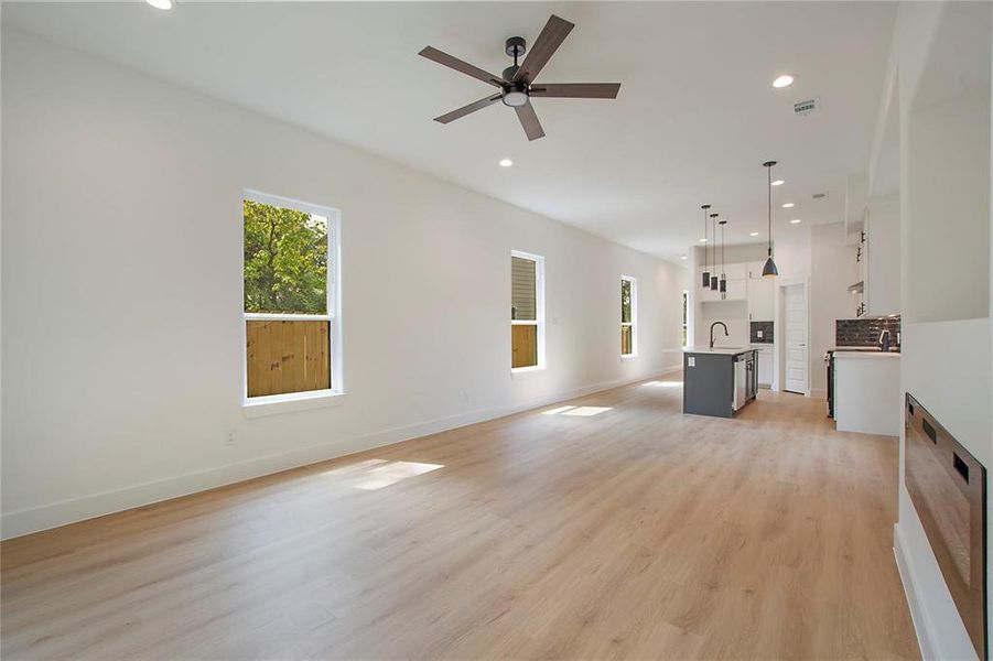 Unfurnished living room featuring ceiling fan, light hardwood / wood-style flooring, and sink