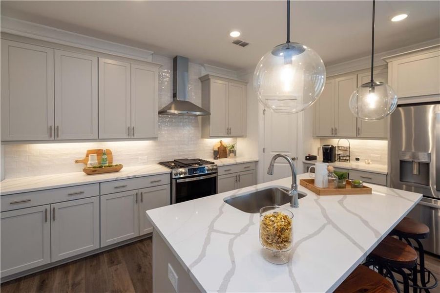 Kitchen with tasteful backsplash, appliances with stainless steel finishes, wall chimney exhaust hood, and sink, refrigirator is not standard , not the actual unit