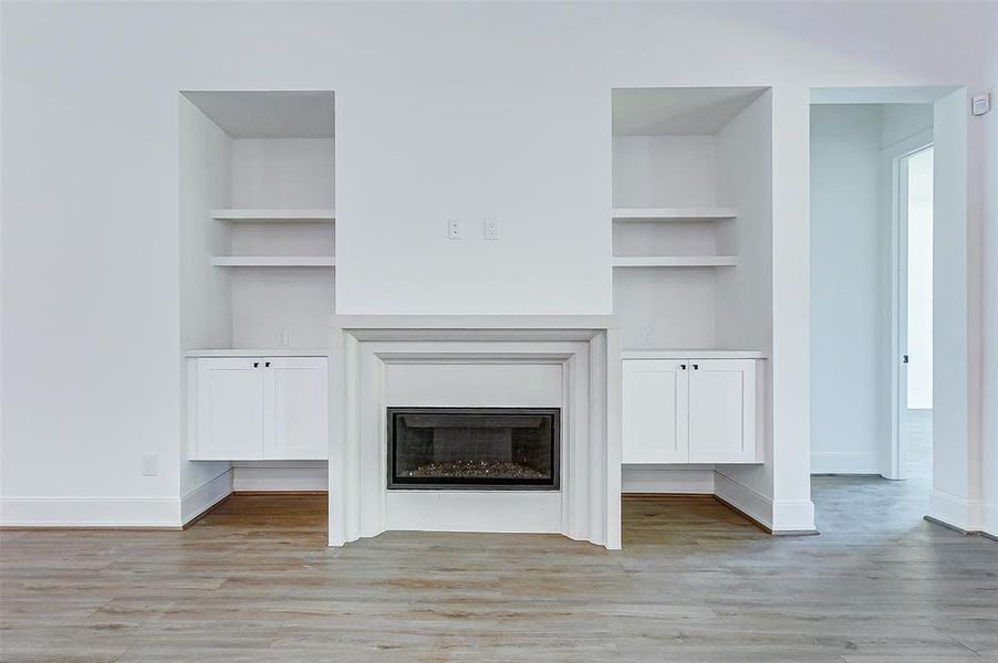 The fireplace is the focal point of the room surrounded by custom built-in shelves and cabinetry.