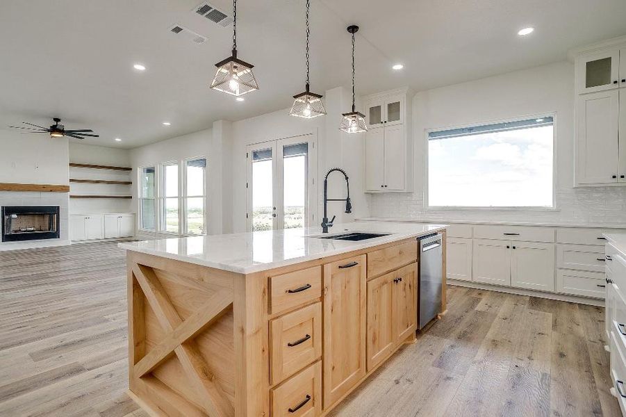 Kitchen with a tile fireplace, light hardwood / wood-style floors, sink, ceiling fan, and decorative backsplash