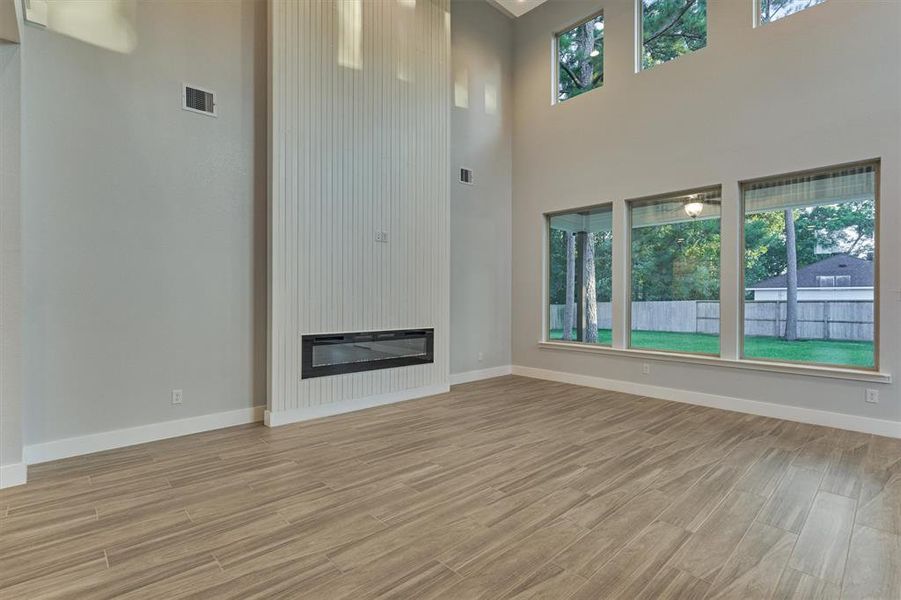 An electric fireplace is surrounded with a modern beadboard. The vertical lines lift the eye up and is a great focal point for the two story space.
