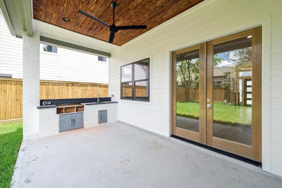 Large patio space is equipped with an outdoor kitchen featuring a grill and sink. Bead board ceiling and large patio over look the spacious backyard with St. Augustine grass, french drains, and 8 ft privacy fence.
