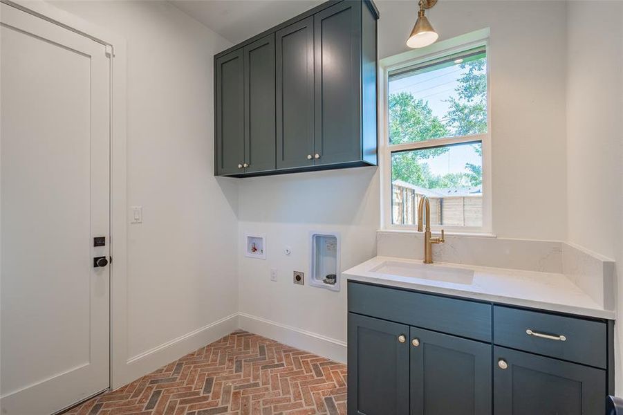 Laundry room featuring herringbone patterned brick floors hookup for a washing machine, sink, hookup for a gas dryer, electric dryer hookup, and cabinets