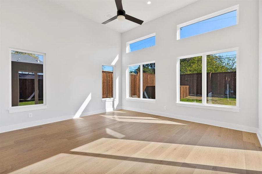 Unfurnished room with hardwood / wood-style floors, ceiling fan, and a high ceiling