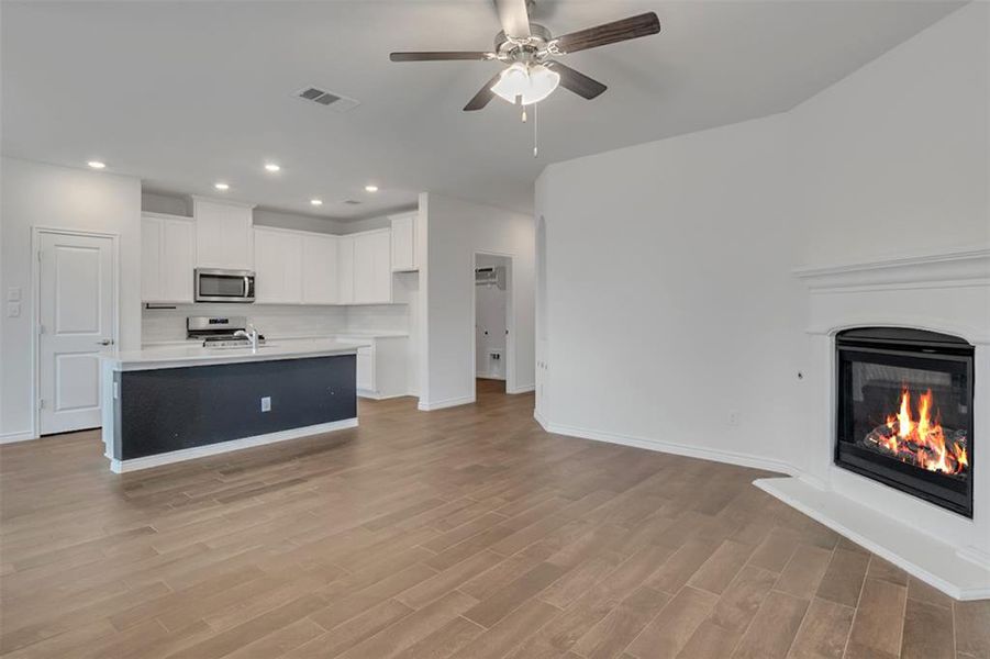 Kitchen featuring white cabinets, ceiling fan, light hardwood / wood-style floors, and a kitchen island with sink