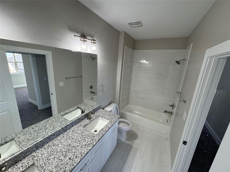 Full bathroom with vanity, tiled shower / bath combo, toilet, and tile patterned floors