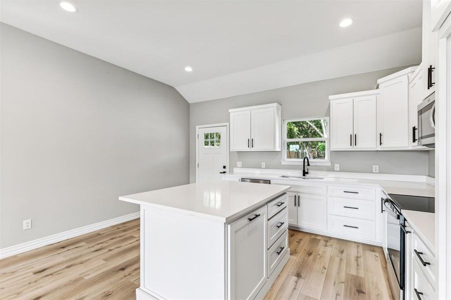 Kitchen with white cabinets, appliances with stainless steel finishes, a center island, and sink