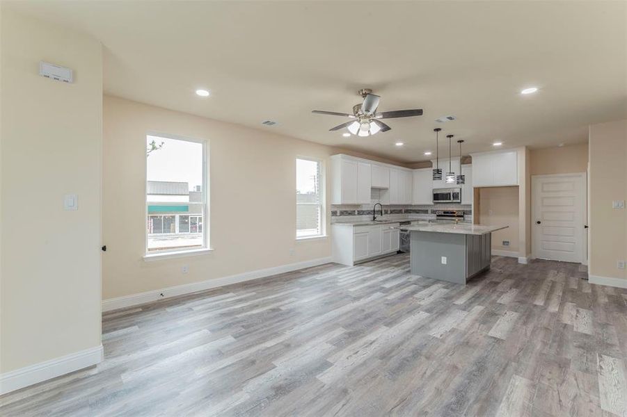 Kitchen featuring white cabinets, light wood-type flooring, appliances with stainless steel finishes, ceiling fan, and a kitchen island