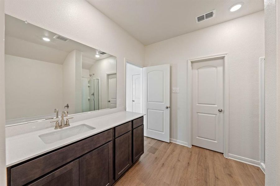 Bathroom featuring vanity, wood-type flooring, and a shower with door