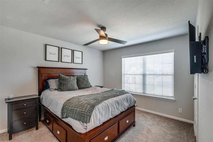 Carpeted bedroom featuring ceiling fan and a textured ceiling