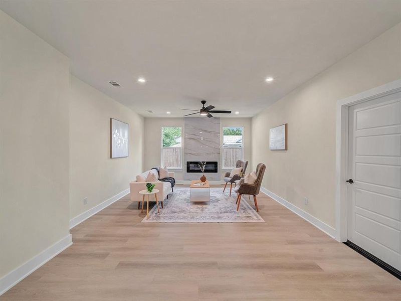 Living room with light hardwood / wood-style flooring, a large fireplace, and ceiling fan