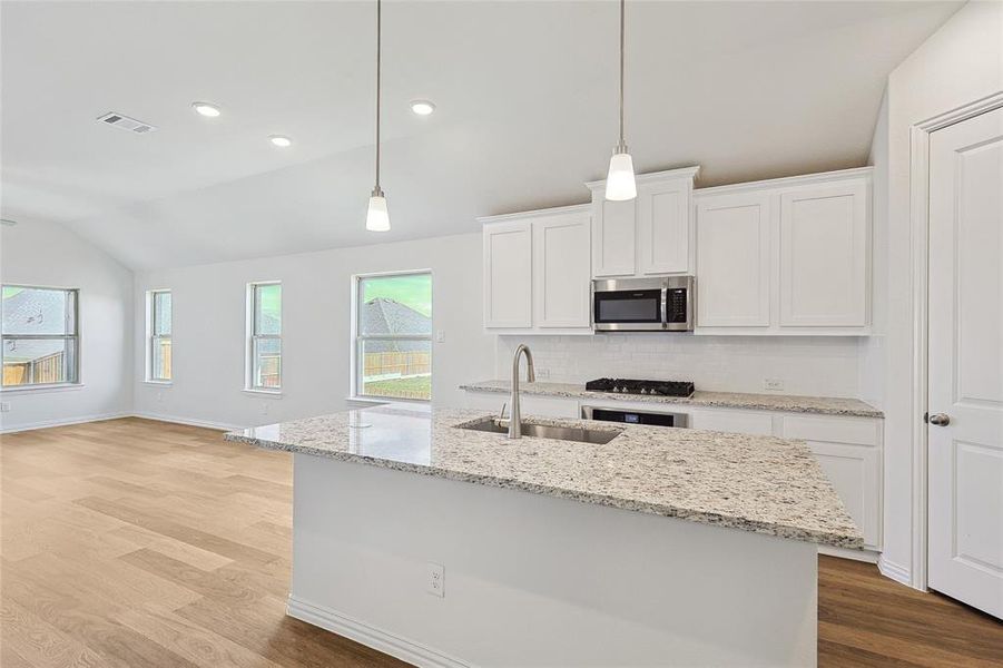 Kitchen with white cabinets, lofted ceiling, and sink