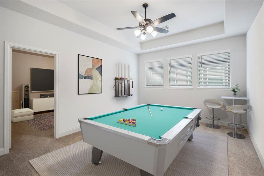 Upstairs you walk into a large game room that's perfect for a pool table, tv's, or a lounging space! It features a trace ceiling, ceiling fan, plush carpet, and three large windows. *This room has been virtually staged