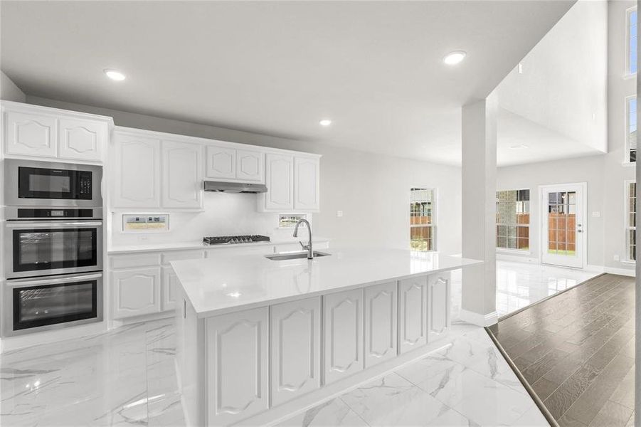 Kitchen featuring white cabinets, a center island with sink, and sink