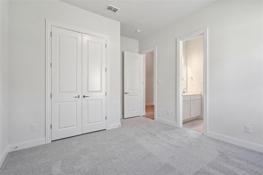 Unfurnished bedroom with ensuite bath, sink, a closet, and light carpet