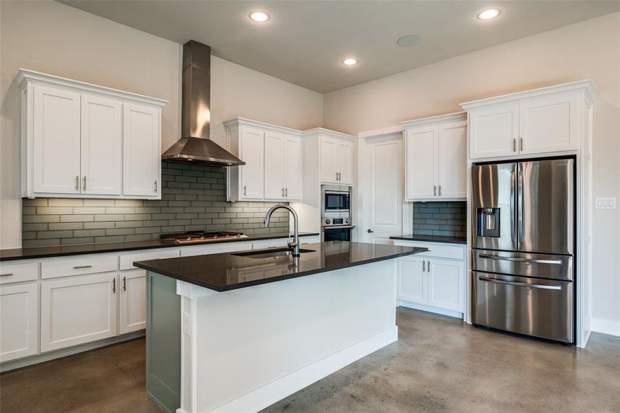 Kitchen with tasteful backsplash, wall chimney range hood, appliances with stainless steel finishes, sink, and white cabinets