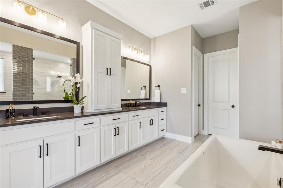 Bathroom featuring vanity, tile patterned floors, and a bath