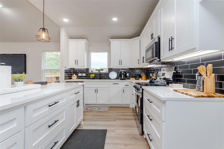 Kitchen featuring white cabinetry, light hardwood / wood-style floors, appliances with stainless steel finishes, and backsplash