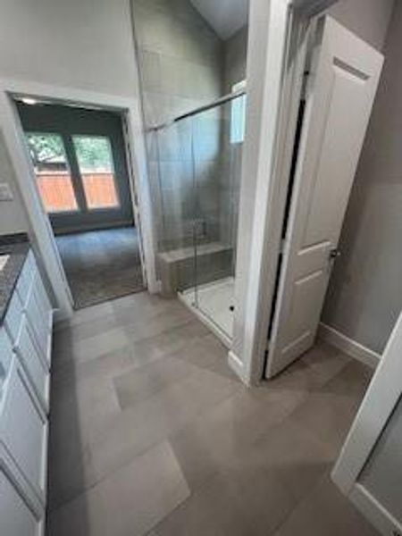 Primary bath features large walk in shower, double sinks, granite and tile flooring
