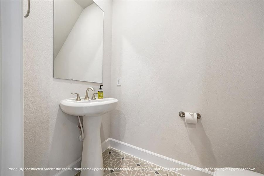 Nestled under the stairs, this powder room features a timeless pedestal sink, combining convenience and classic style.