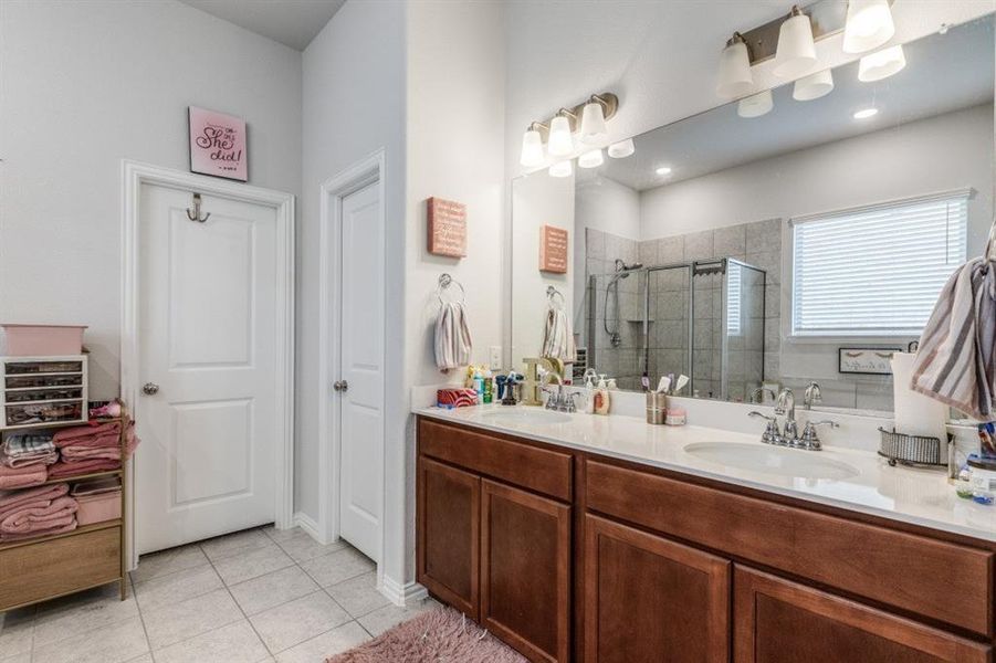 Bathroom with vanity, a shower with shower door, and tile patterned floors