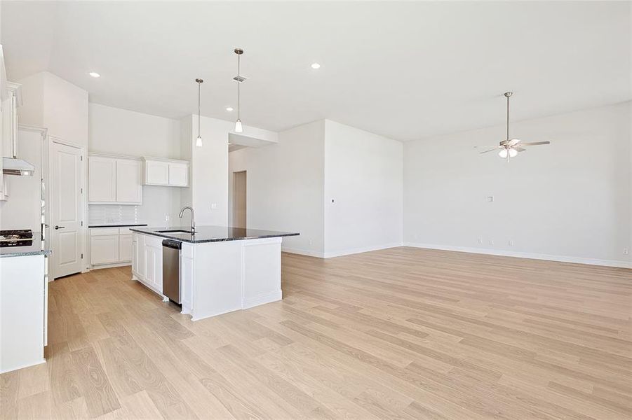 Kitchen with light hardwood / wood-style flooring, white cabinetry, stainless steel dishwasher, a kitchen island with sink, and ceiling fan