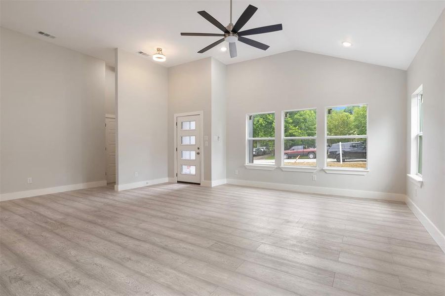 Unfurnished living room with high vaulted ceiling, ceiling fan, and light hardwood / wood-style floors