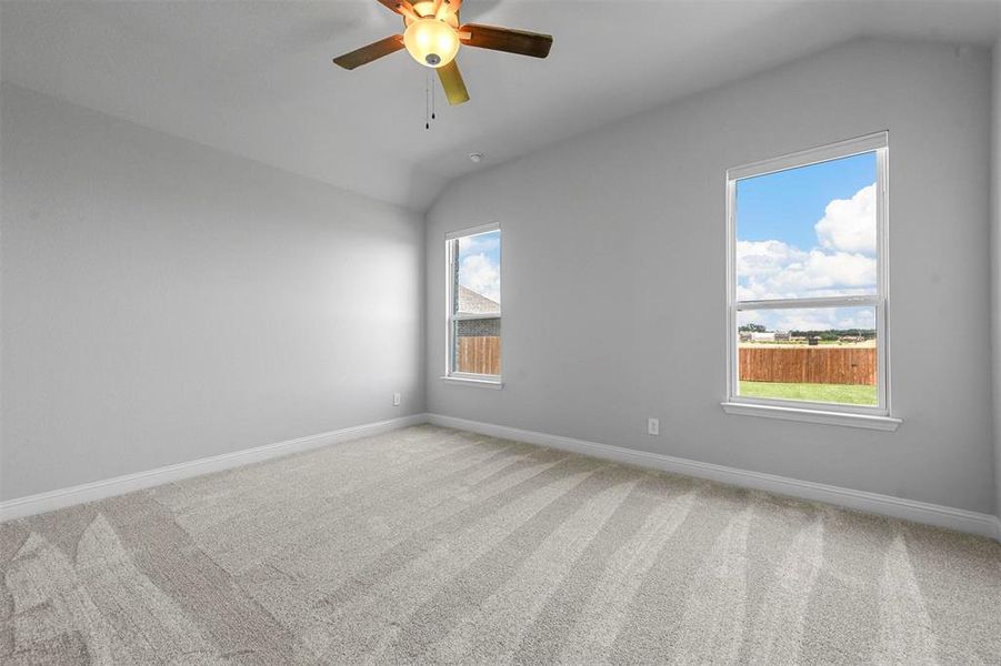 Unfurnished room featuring carpet, ceiling fan, and vaulted ceiling