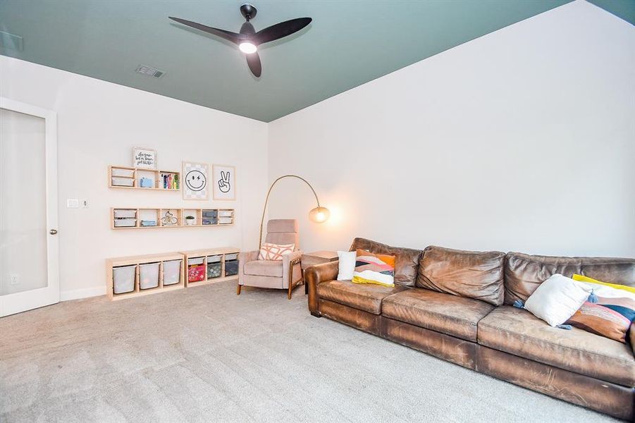 Spacious, well-lit game room featuring a vaulted ceiling with a contrasting paint accent, large windows providing ample natural light, double doors with glass accent. New carpet creates a clean, inviting space. a ceiling fan.