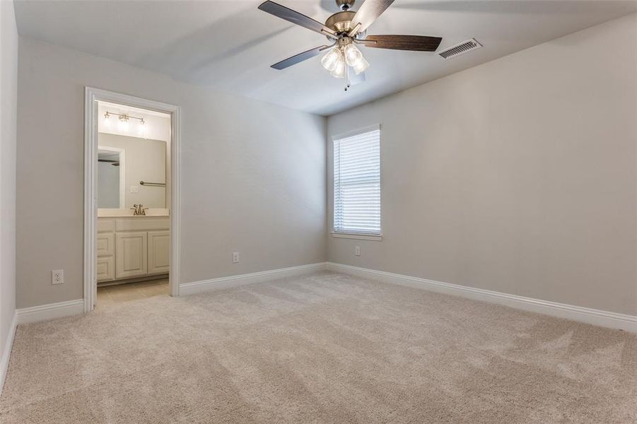 Unfurnished bedroom with sink, connected bathroom, ceiling fan, and light colored carpet