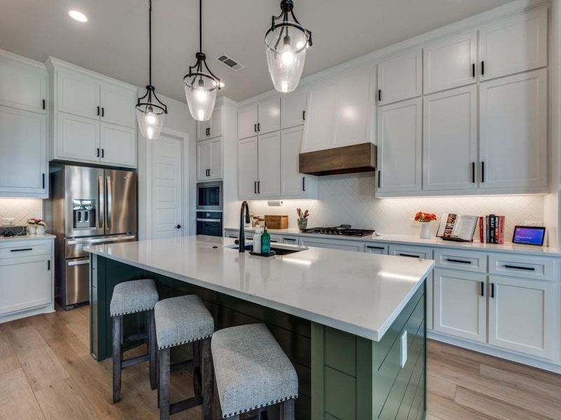 Kitchen with appliances with stainless steel finishes, light hardwood / wood-style flooring, a center island with sink, and white cabinets