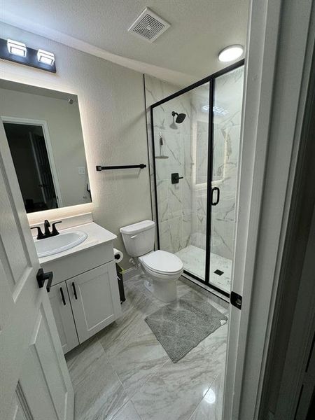 Bathroom with tile floors, an enclosed shower, toilet, and vanity