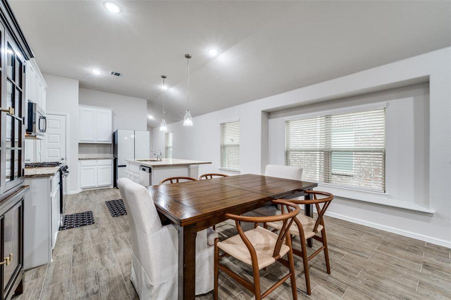 Dining room with vaulted ceiling, sink, and light wood-type flooring