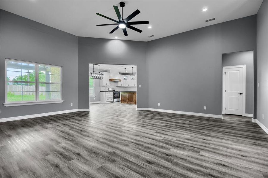 Unfurnished living room featuring a high ceiling, dark hardwood / wood-style floors, and ceiling fan