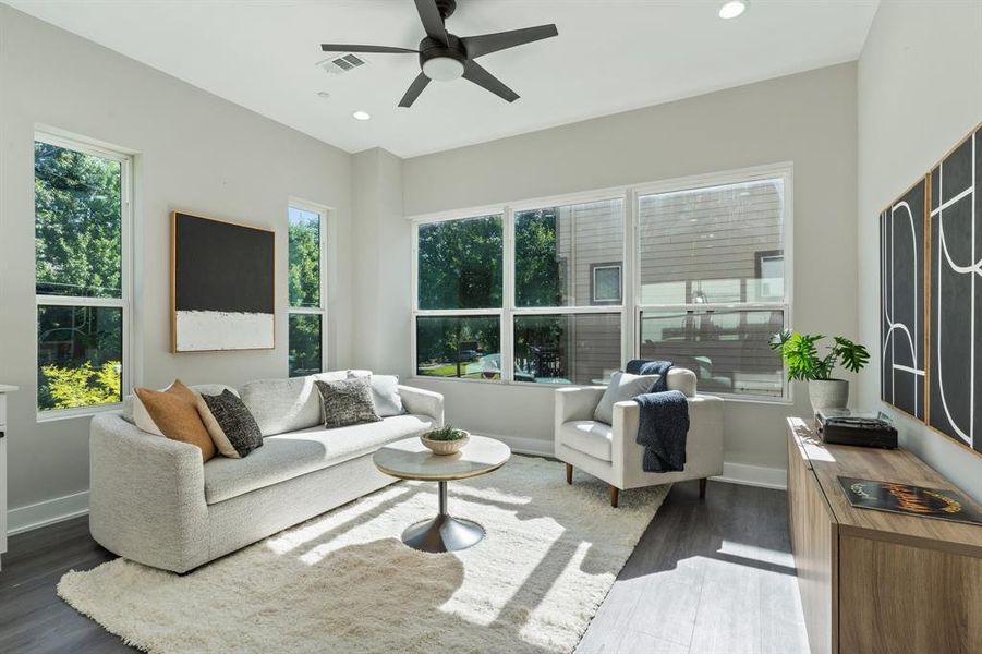 Living room with dark hardwood / wood-style flooring, a wealth of natural light, and ceiling fan