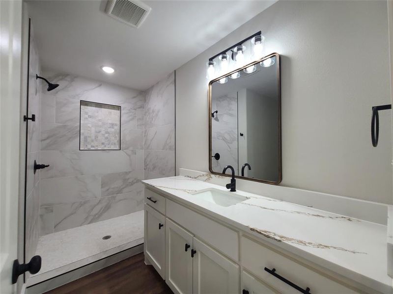 Bathroom featuring tiled shower, hardwood / wood-style floors, and vanity
