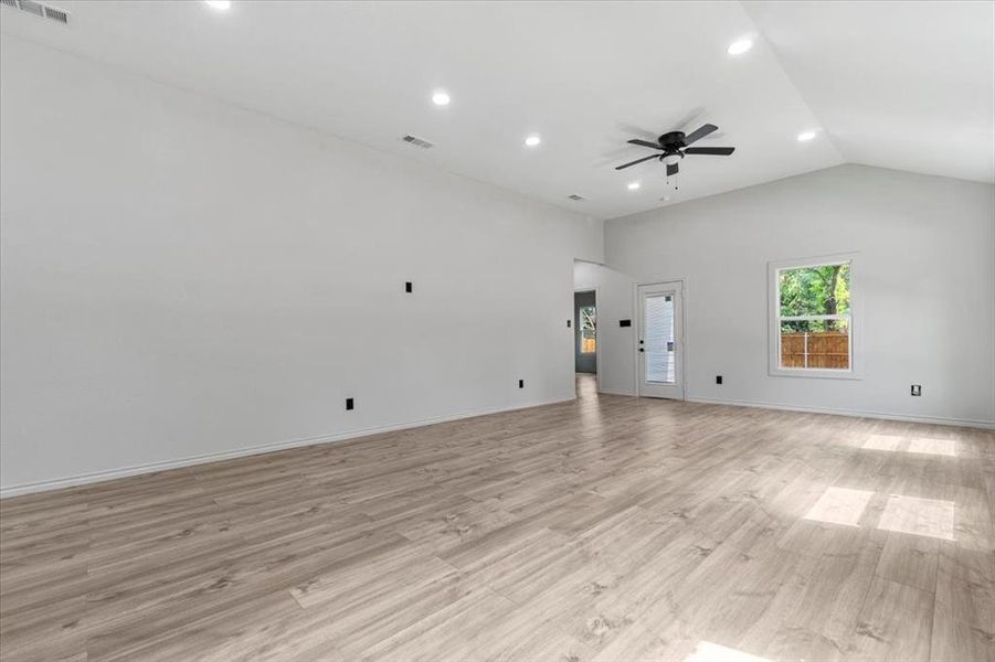 Unfurnished living room featuring lofted ceiling, light hardwood / wood-style floors, and ceiling fan