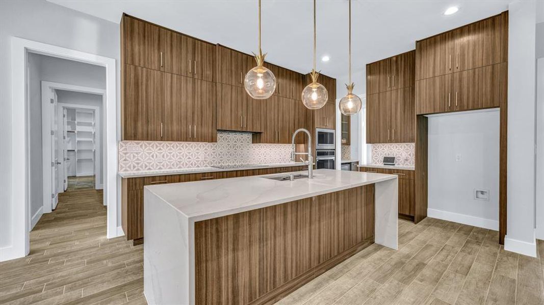 Kitchen featuring appliances with stainless steel finishes, sink, light hardwood / wood-style floors, and a large island