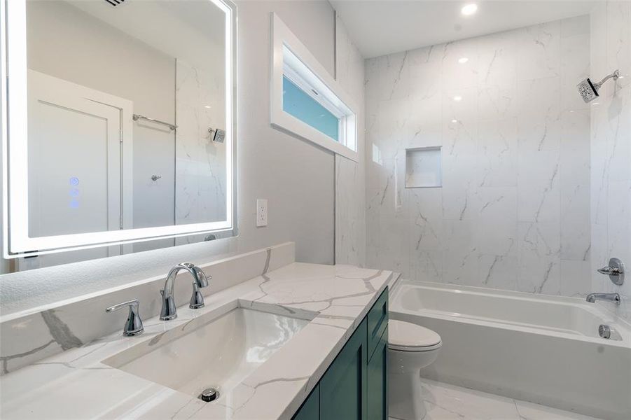 Full bathroom with vanity, tiled shower / bath, and toilet