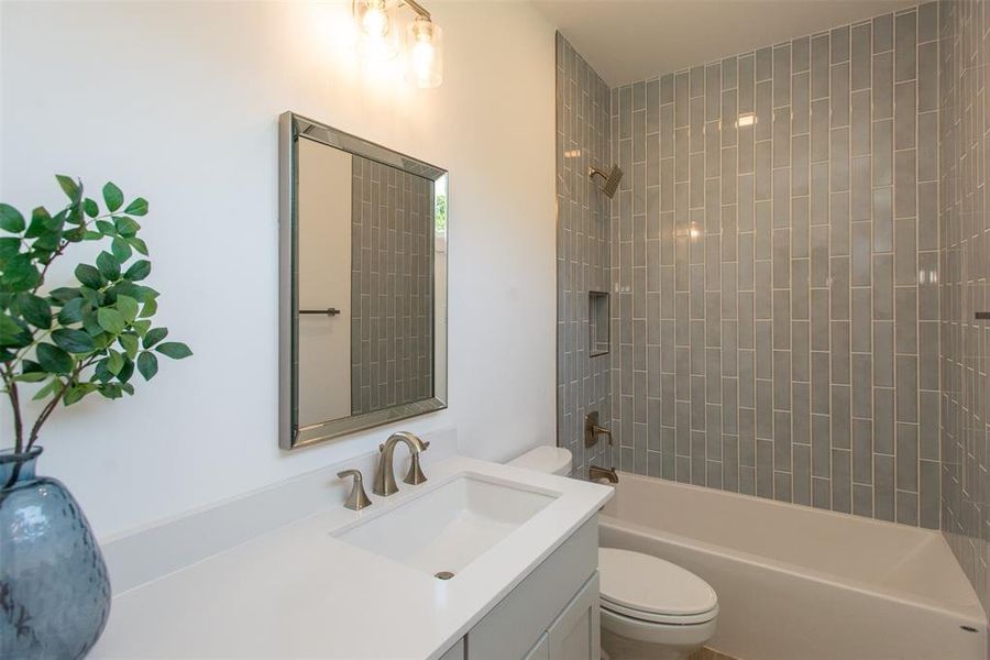 Full bathroom with tiled shower / bath, vanity, and toilet