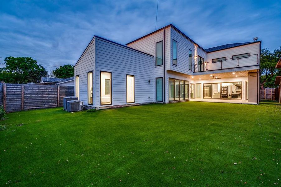 Rear view of property featuring a patio area, a lawn, a balcony, and central AC unit