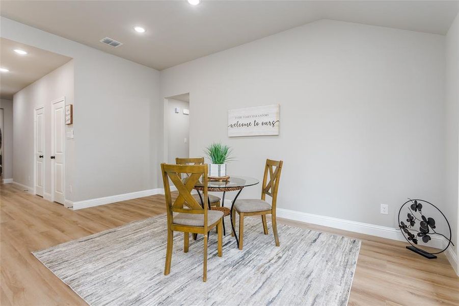 Dining area with vaulted ceiling and light hardwood / wood-style flooring