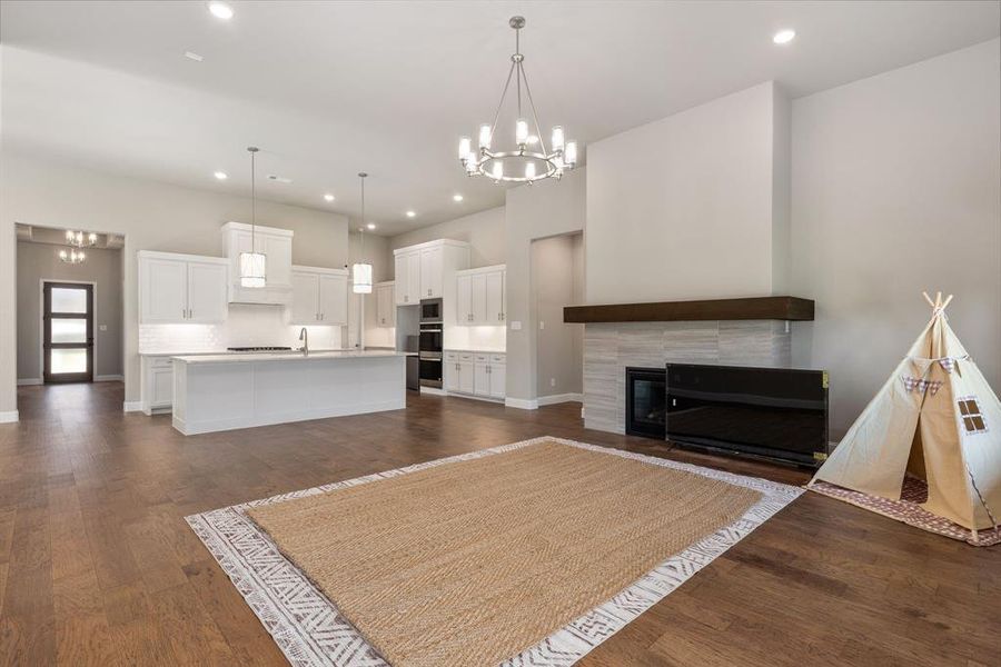 Unfurnished living room with a tile fireplace, sink, dark wood-type flooring, and a notable chandelier