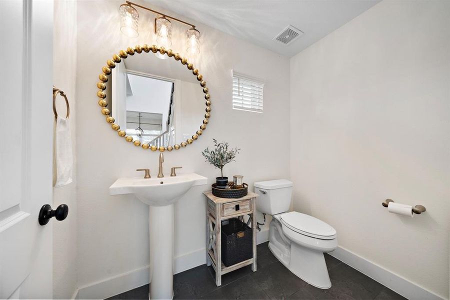 The half bath is adorned with a custom mirror, basking in just the right amount of natural light.