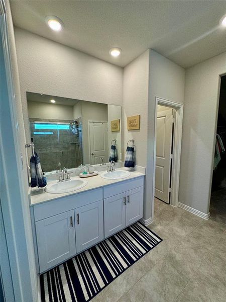 Bathroom with a textured ceiling, a shower with shower door, and vanity