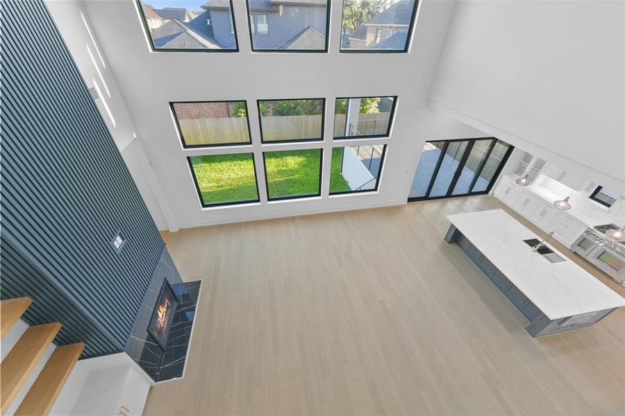 An expansive living area with floor to ceiling windows that provide views of the backyard, Coffered ceiling, floating shelves for decoration and function as well as a fireplace is the perfect space for entertaining.