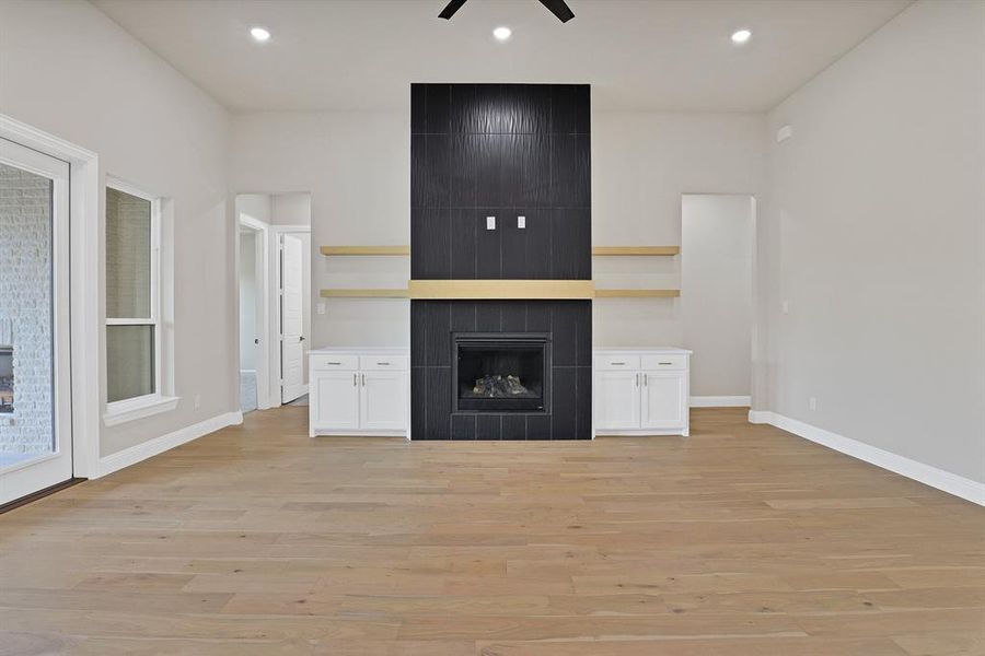 Unfurnished living room featuring a fireplace, ceiling fan, and light hardwood / wood-style floors