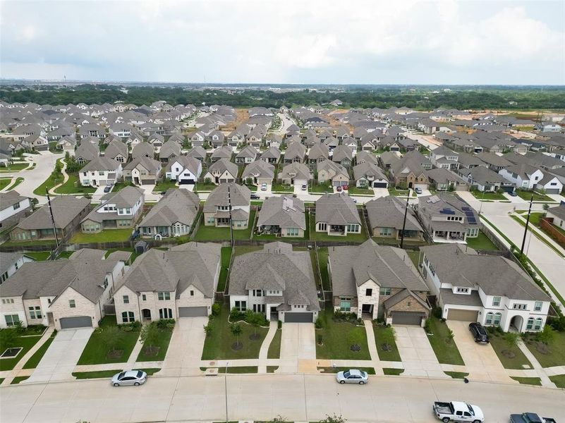 You're looking at an aerial view of a modern suburban neighborhood with spacious single-family homes, well-manicured lawns, and attached garages. The community appears to be recently developed, with uniform architecture and clean, winding streets.
